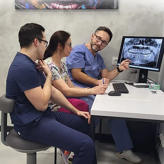 Troje lekarzy analizuje pantomogram na monitorze w gabinecie