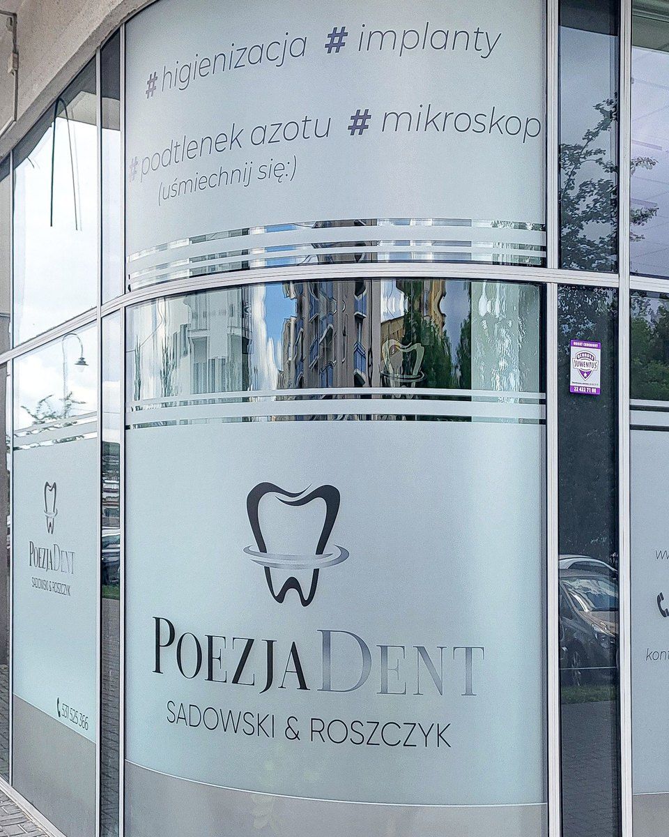 Narożne oszklenie lokalu z nazwą kliniki i znakiem, widziane z chodnika